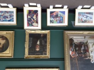 a row of paintings propped against a gallery wall