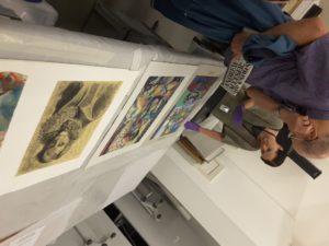 People viewing drawings and paintings at a table